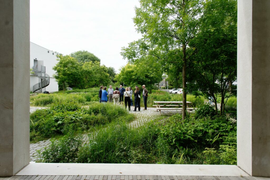 Groep mensen in natuur vanuit gebouw gefotografeerd. Jury NRP Gulden Fenix